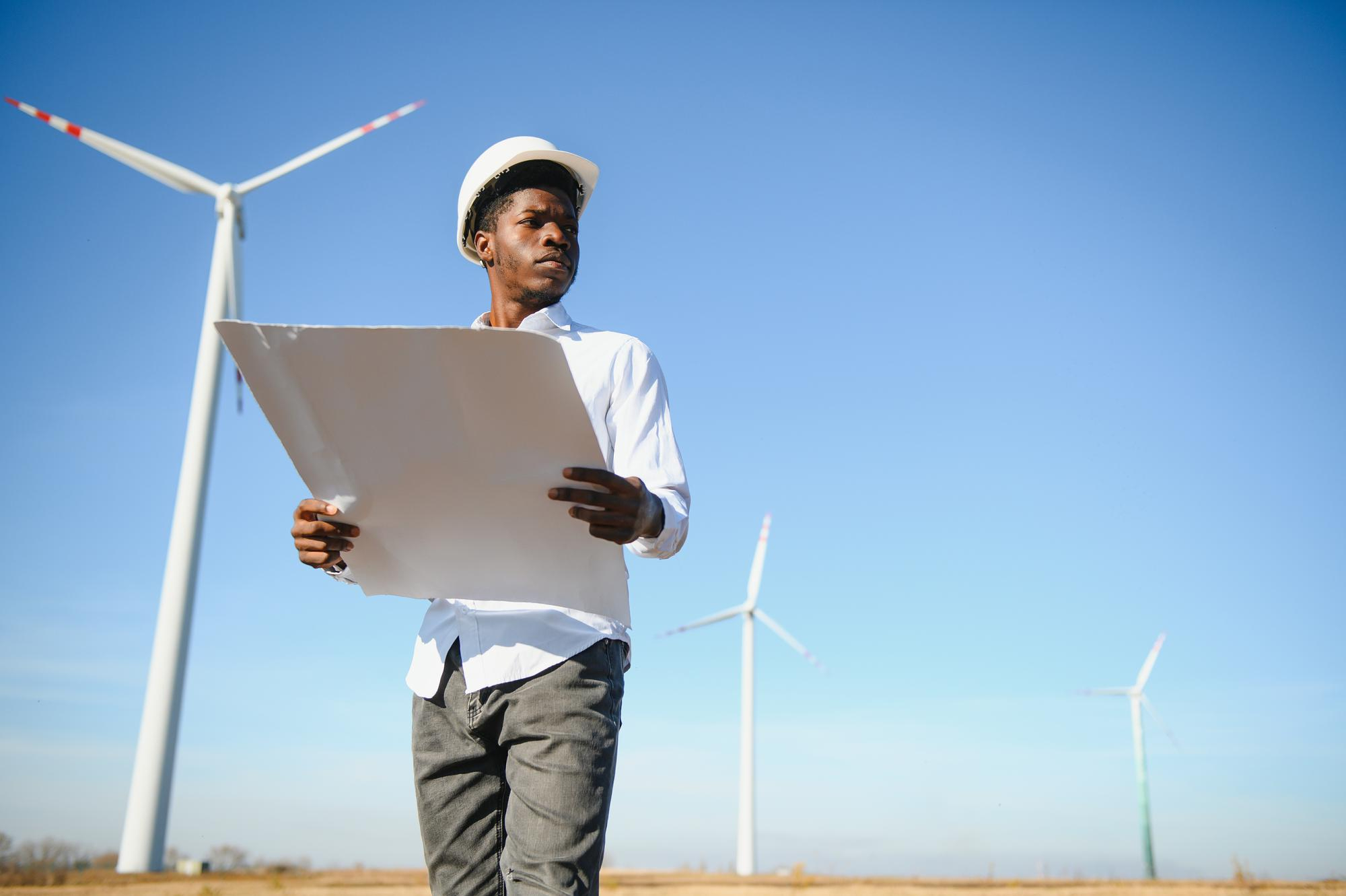 Young energy professional reviewing infrastructure plans near wind turbines