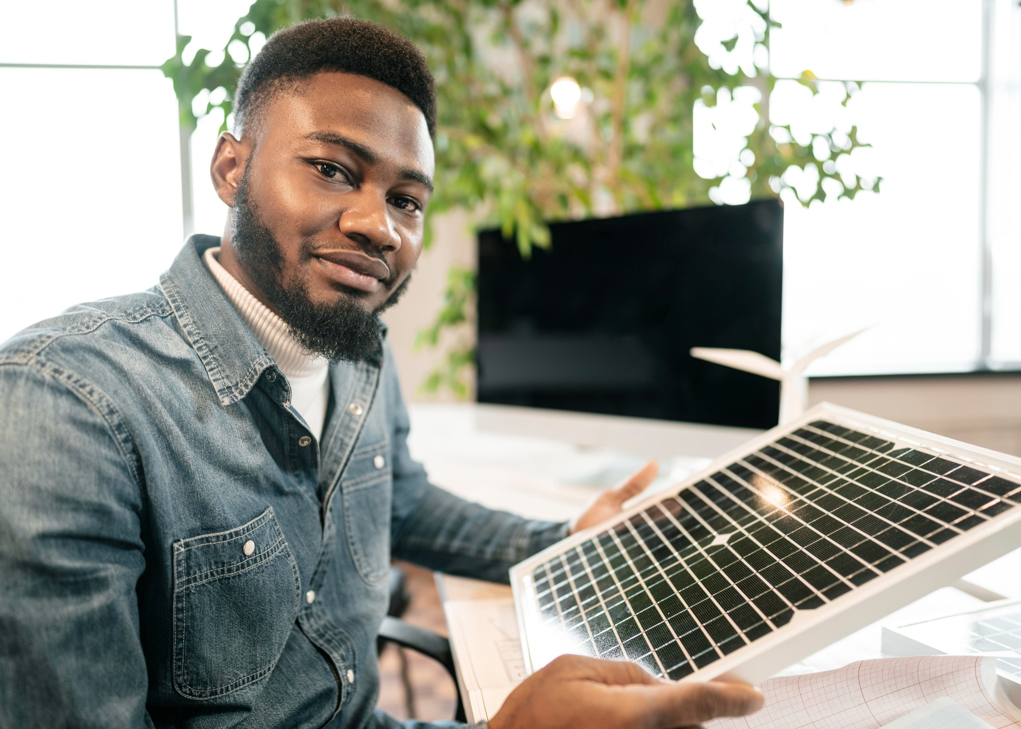 African clean-energy founder holding a solar panel model