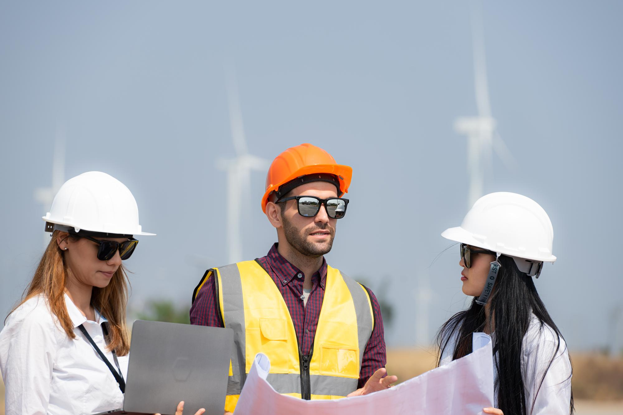 Energy professionals collaborating beside wind turbines